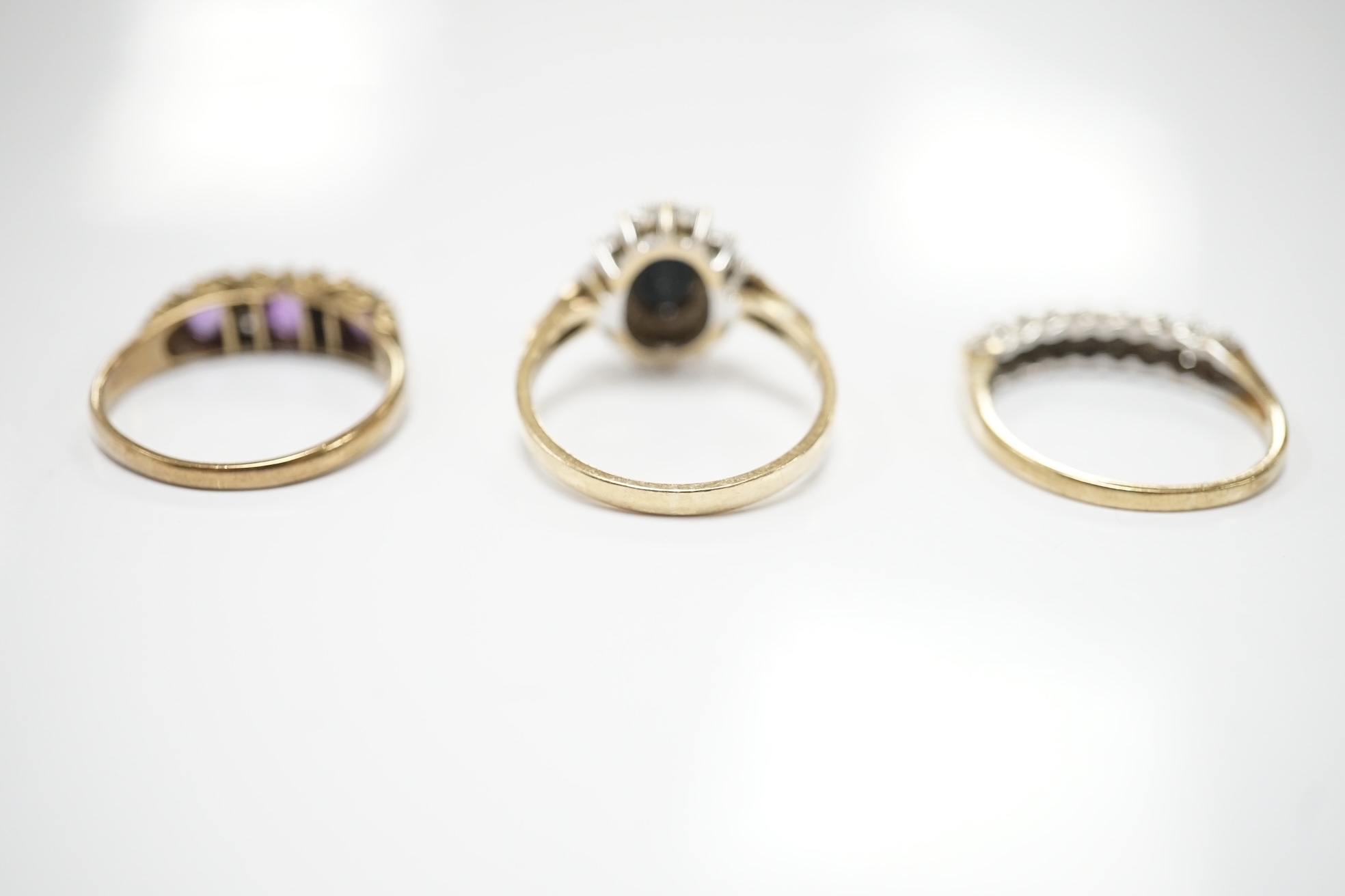 Three assorted 9ct and gem set rings including a diamond chip cluster half hoop and two pairs of yellow metal and gem set ear studs including sapphire? and diamond cluster. Condition - fair to good